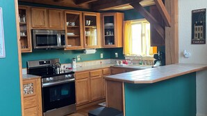 A kitchen with wooden cabinets, a stainless steel stove, and a trash bin.
