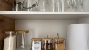 Ein Küchenregal mit Glasbehältern, einer Kaffeemaschine und Weingläsern.