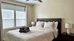 A bedroom with a bed, two bedside lamps, a window with blinds, and a ceiling fan. - Historic Downtown Visalia 2BR • 1BA (Visalia)