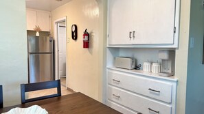 Une cuisine équipée d’un réfrigérateur, d’un grille-pain et d’une machine à café, le tout posé sur le plan de travail.