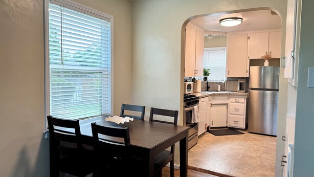 A compact kitchen with a dining table, chairs, and basic appliances. - Historic Downtown Visalia 2BR • 1BA (Visalia)