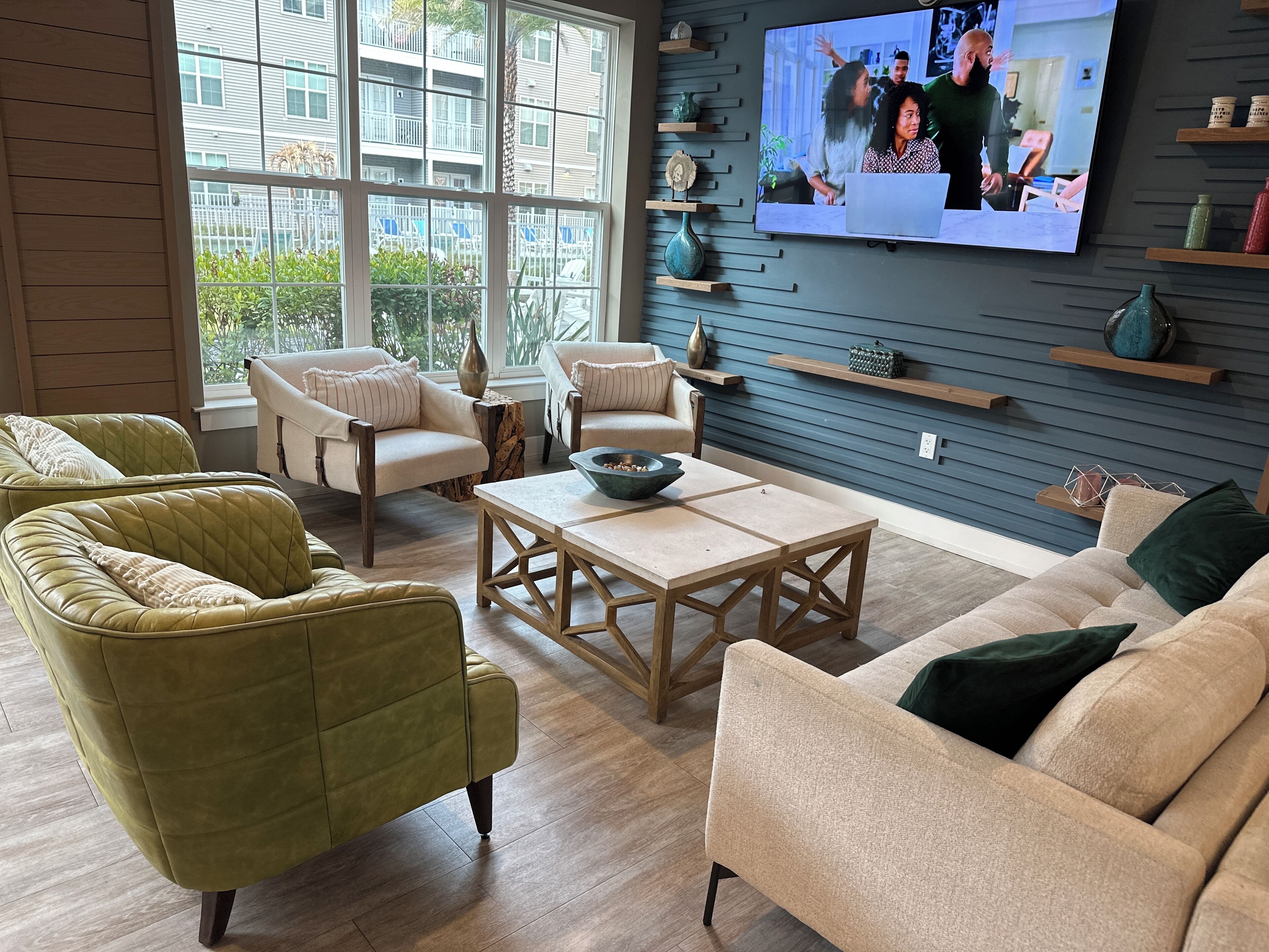 Un salon moderne doté d’une grande fenêtre, d’un téléviseur à écran plat et d’une table basse en bois.