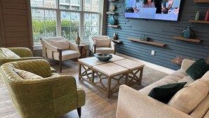 Ein modernes Wohnzimmer mit einem großen Fenster, einem Flachbildfernseher und einem Holztisch.