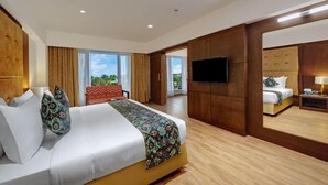 A hotel room with a bed, a TV, a desk, and a large window. - The Fern Residency Satara Maharashtra (Satara)
