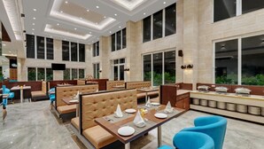 A spacious restaurant with high ceilings, large windows, and a modern interior design. - The Fern Residency Satara Maharashtra (Satara)
