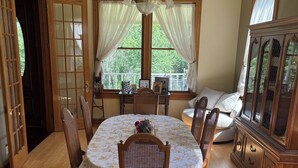 Una sala da pranzo con un tavolo rotondo, sedie, un lampadario e un mobiletto in legno.