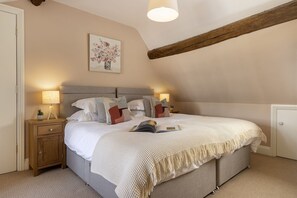 Ein Schlafzimmer mit einem Bett, Nachttischlampen, einem Nachttisch, einem kleinen Tisch und einem Gemälde an der Wand.