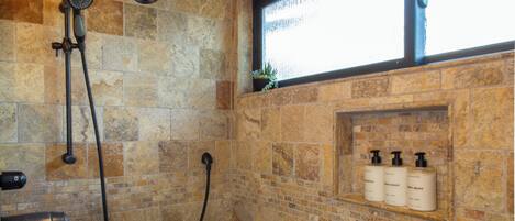 A stone-walled shower with a handheld showerhead and a wall-mounted faucet.