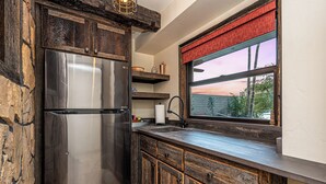 Eine Küche mit einem Edelstahl-Kühlschrank, Holzschränken, einem Fenster mit Aussicht und einem Spülbecken mit Armatur.