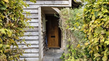 Un bâtiment en bois avec une porte et un petit marchepied menant à l’entrée.