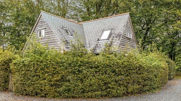A house with a sloped roof, surrounded by dense green foliage.
