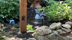 A garden with a wooden post, a bird bath, and potted plants. - Historic Block Island Suite (New Shoreham)