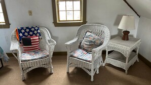 A room with two wicker chairs, a small table, and a window. - Historic Block Island Suite (New Shoreham)