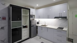 A modern kitchen with white cabinets, a black refrigerator, a microwave, and a sink. - Kandy Haven - Studio Type Unit (Angeles City)