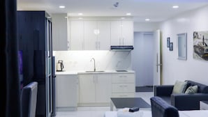 A modern kitchen with white cabinets, a black range hood, and a marble countertop. - Kandy Haven - Studio Type Unit (Angeles City)