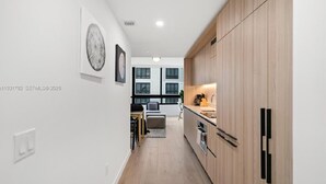 Een moderne keuken met houten kastjes, een eethoek met een tafel en stoelen, en kunst aan de muren.