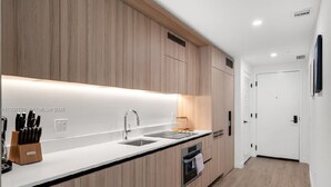 Een moderne keuken met houten kastjes, een wit aanrecht, een spoelbak en een inbouwoven.