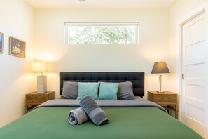 Ein Schlafzimmer mit einem Bett, zwei Nachttischen, einem Fenster und einer Tür.