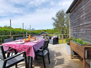 An outdoor dining area with a table set for breakfast, surrounded by chairs and a wooden deck. - Ty Stef by Interhome (Nevez)