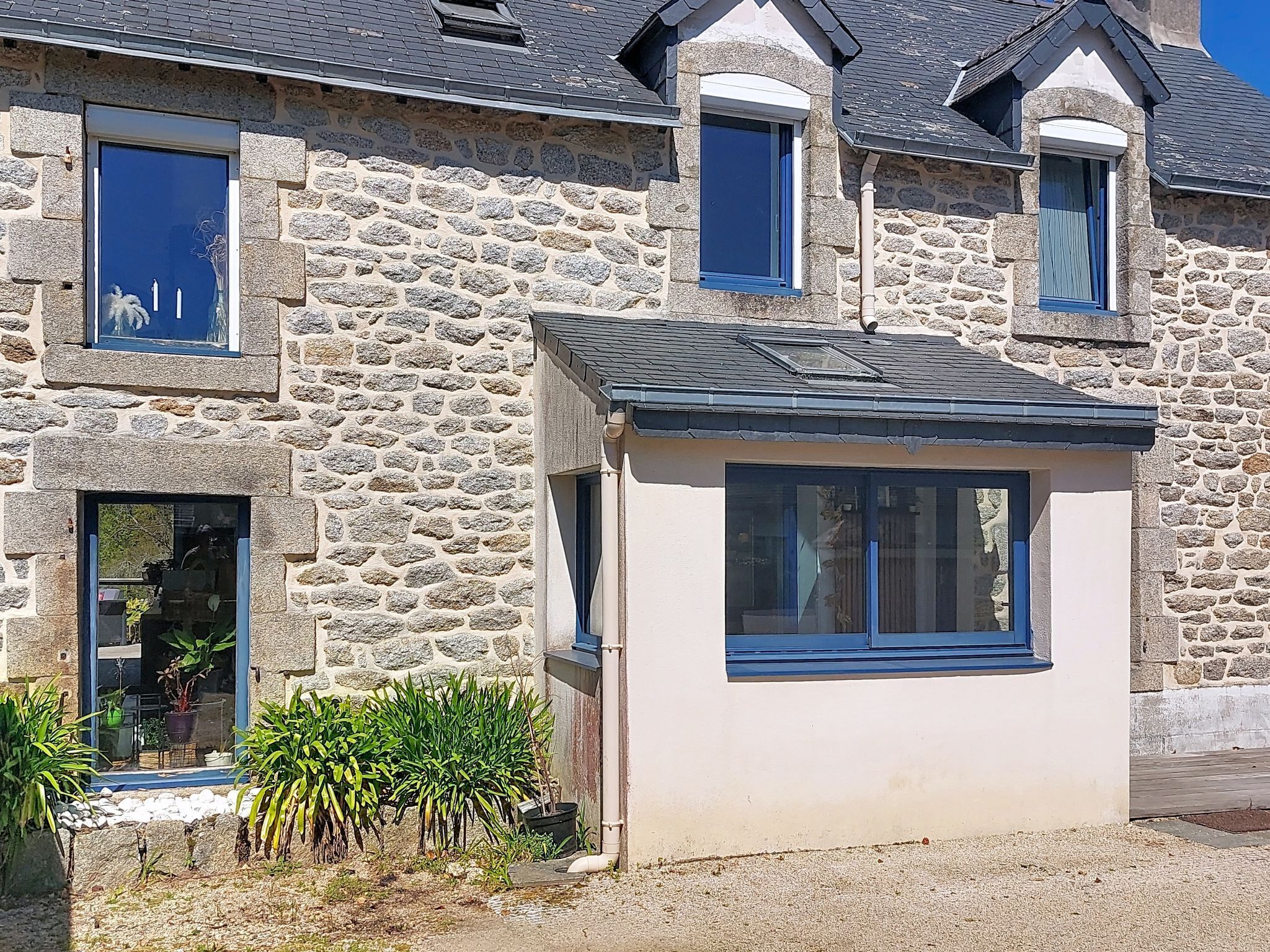 A stone house with multiple windows and a small attached structure.