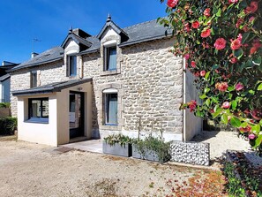 A stone house with a small attached structure, a gravel driveway, and a rose bush. - Ty Stef by Interhome (Nevez)
