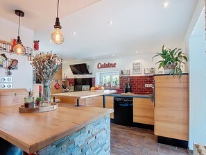 A modern kitchen with a central island, hanging pendant lights, and a brick accent wall. - Ty Stef by Interhome (Nevez)