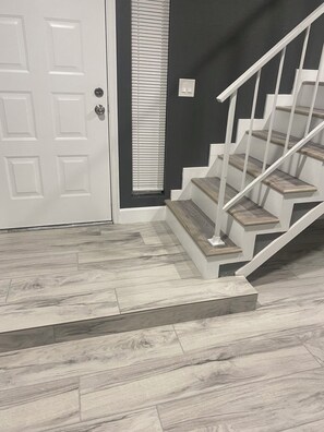 A staircase with wooden steps and white railings, a white door with a keyhole, and a dark wall with a window. - Wonderful 3-bedroom house with AC in sunny Phoenix (Phoenix)