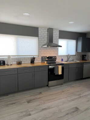 A modern kitchen with grey cabinets, a stainless steel range hood, and a wooden countertop. - Wonderful 3-bedroom house with AC in sunny Phoenix (Phoenix)