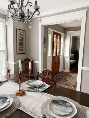 Comedor con candelabro, obra de arte enmarcadas y puerta de madera con vidrieras.