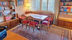 A cozy room with a wooden table, chairs, a bookshelf, and a window with curtains. - Rüttimätteli by Interhome (Marbach)