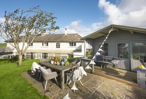 Een huis met een patio, een eettafel met stoelen en een tuin.