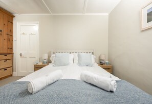 Une chambre à coucher avec un lit, deux tables de chevet, une armoire et un tableau encadré au mur.