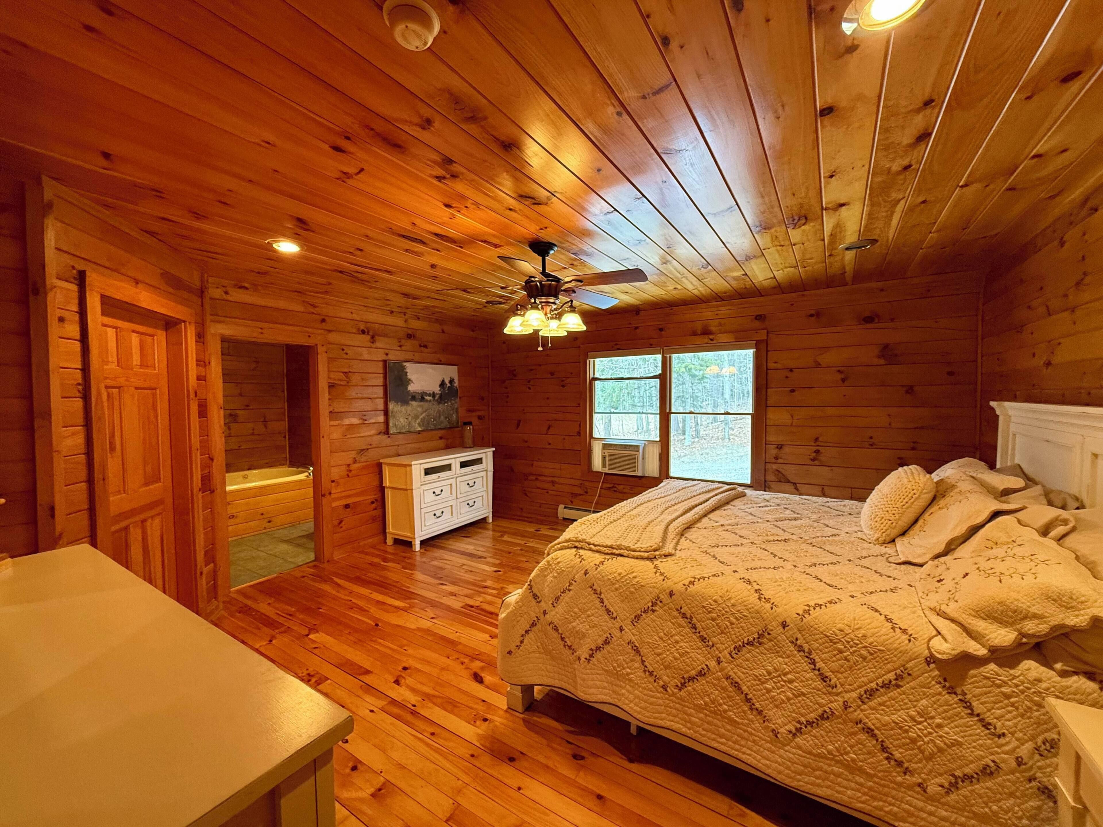 Ein Schlafzimmer einer Holzhütte mit Bett, Schminktisch und Deckenventilator.