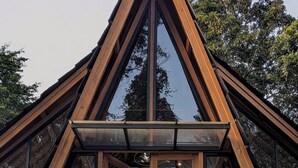 Un edificio moderno con estructura de techo triangular, amplios ventanales y base de piedra.