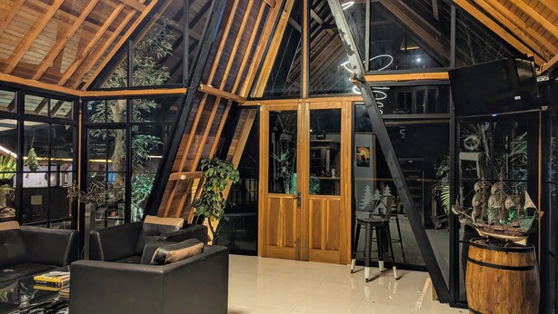 Un interior espacioso con techo alto, vigas de madera y ventanas amplias.