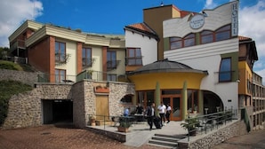 A hotel with a distinctive architectural style, featuring a central dome, multiple balconies, and a stone facade. - Hotel Millennium (Pecs)
