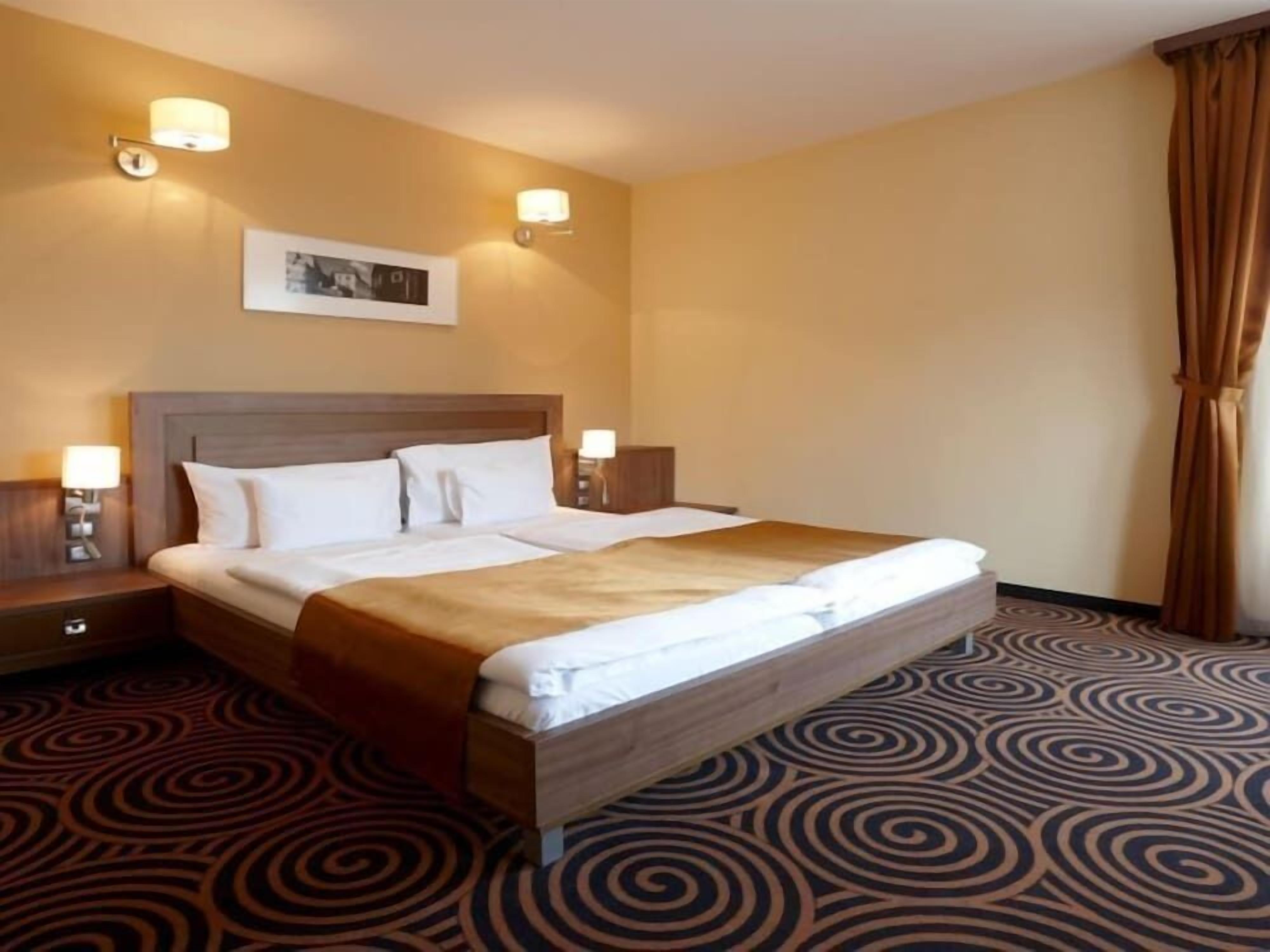 A hotel room with a large bed, two bedside tables, and a headboard.