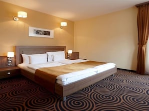 A hotel room with a large bed, two bedside tables, and a headboard. - Hotel Millennium (Pecs)