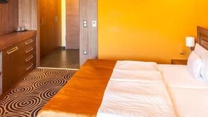 A hotel room with a bed, a desk, and a wardrobe. - Hotel Millennium (Pecs)
