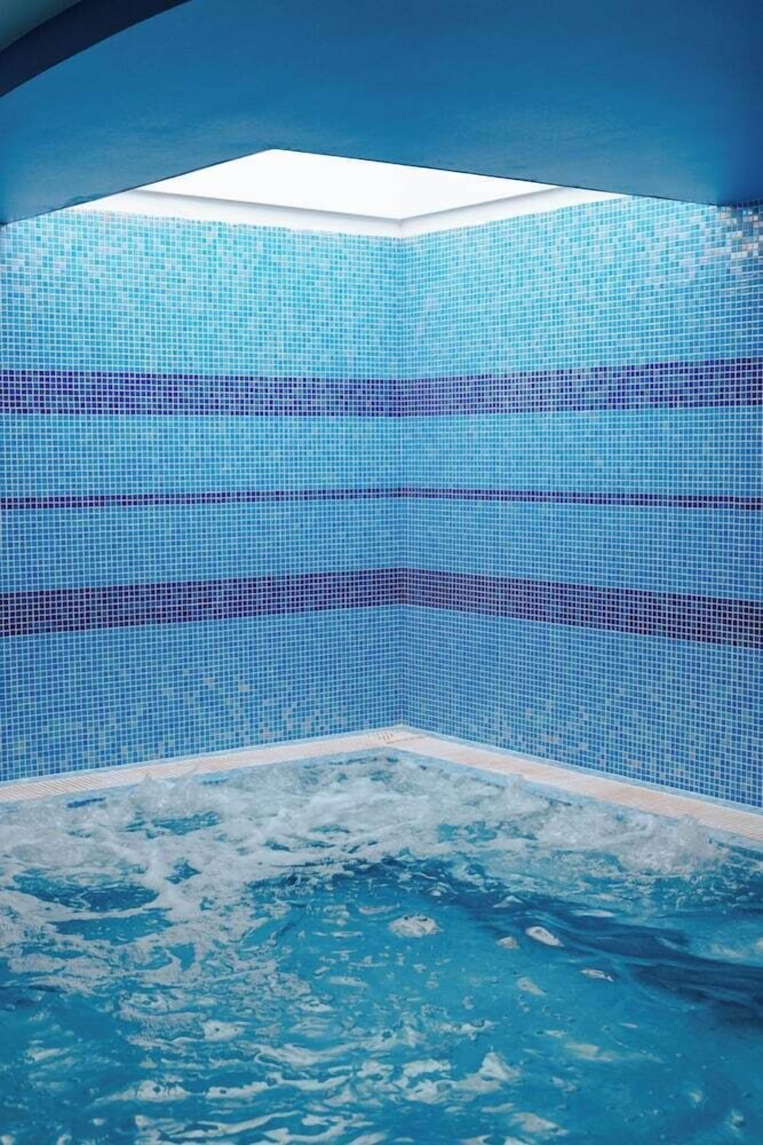 A swimming pool with a tiled interior and a skylight above.