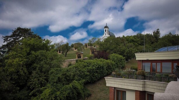 A building with a dome, surrounded by greenery and trees. - Hotel Millennium (Pecs)