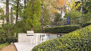 A patio area with a grill, white outdoor furniture, and a stone wall. - Lovely stay by the Braves / 2bd 2bth with private access gate to Braves Stadium (Smyrna)