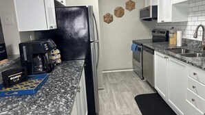 A kitchen with white cabinets, a black refrigerator, a coffee maker, and a microwave. - Lovely stay by the Braves / 2bd 2bth with private access gate to Braves Stadium (Smyrna)