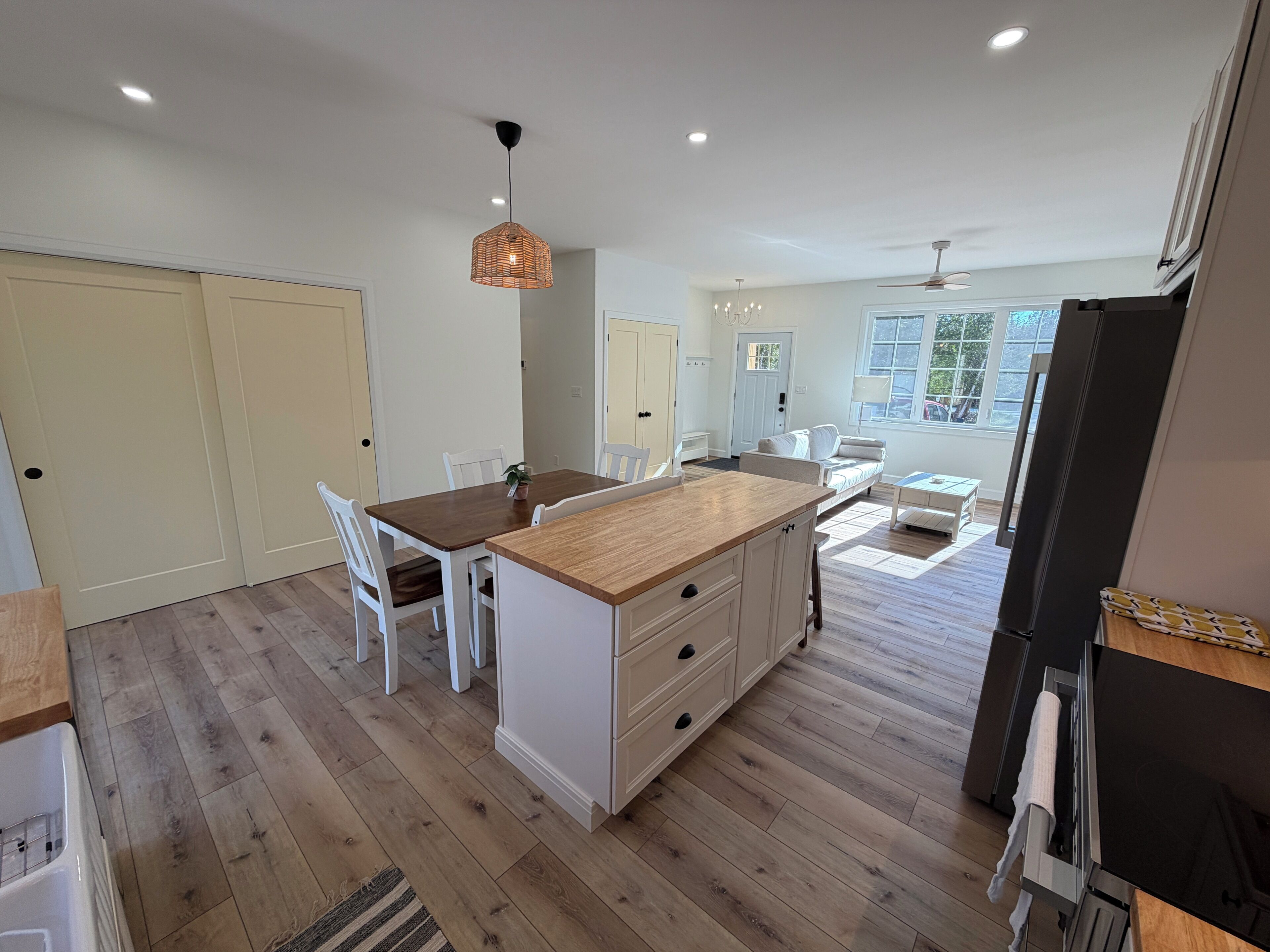 A modern kitchen with a central island, white cabinetry, and a dining area with chairs.