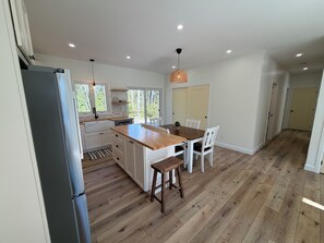 Une cuisine spacieuse avec un îlot central en bois, des meubles blancs et une grande fenêtre.