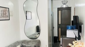 A living area with a grey sofa, a wooden coffee table, a mirror, and a small potted plant. - Modern Studio on Kiambu Rd, Near CBD, JKIA & UN, Walk to Two Rivers/Fast WiFi (Nairobi County)