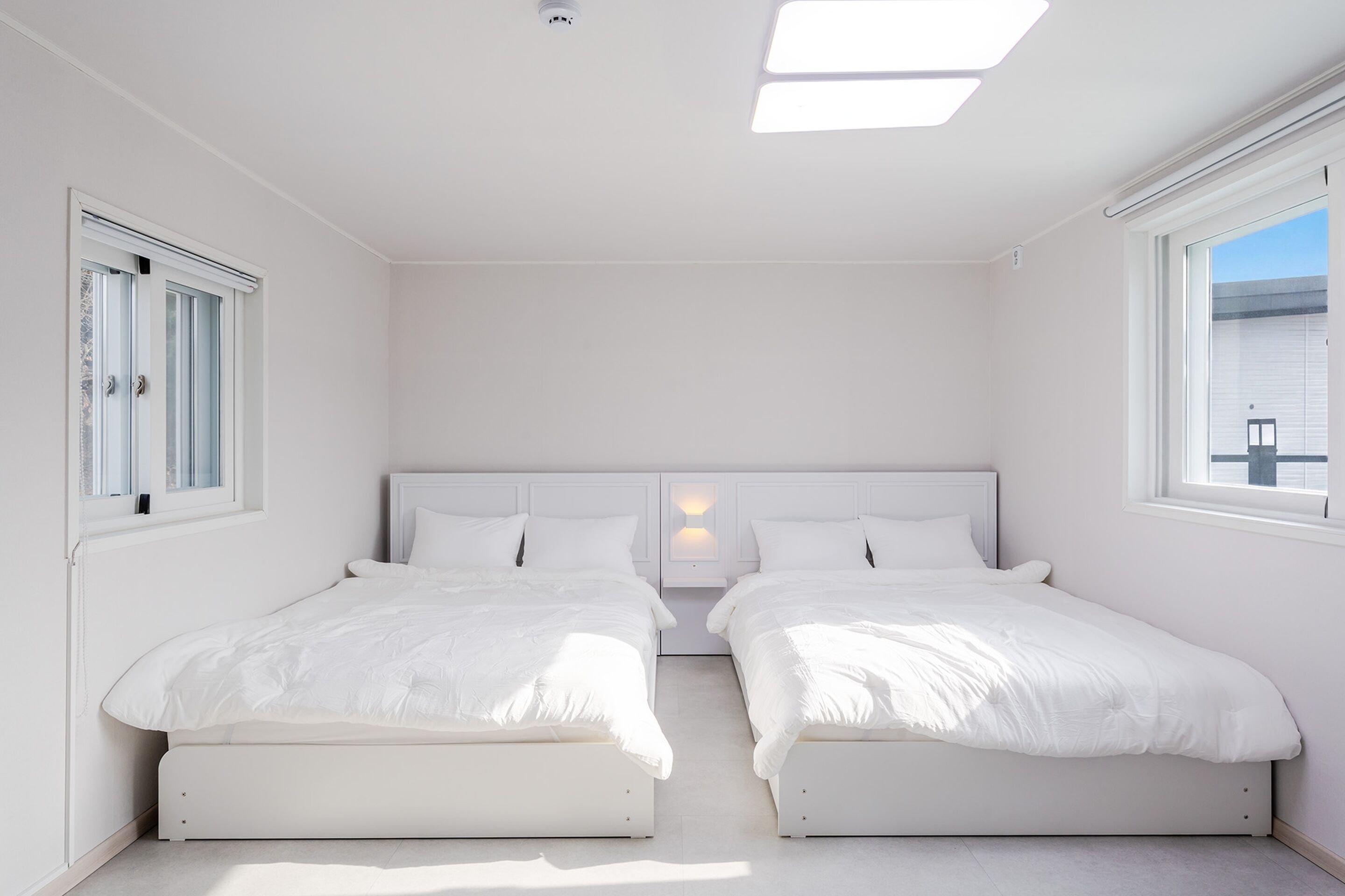 A bedroom with two beds, a skylight, and a window.