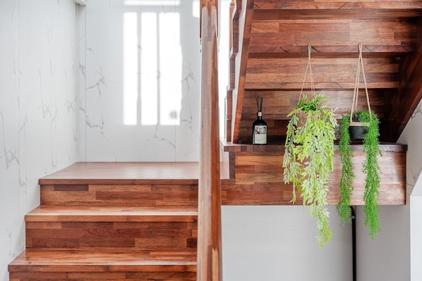 A wooden staircase with a white wall and a window casting light.
