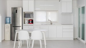 A modern kitchen with white cabinetry, a stainless steel refrigerator, a microwave, and a water dispenser. - Yeongheungdo Jeongwonstay (Incheon)