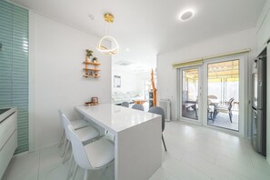 Een moderne keuken met een centraal eiland, witte kasten en een eethoek met een tafel en stoelen.